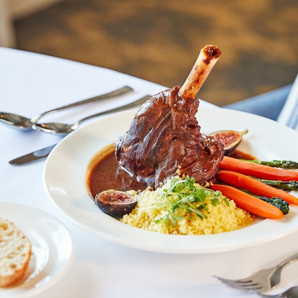 A dish featuring a lamp chop and carrots on a white plate.