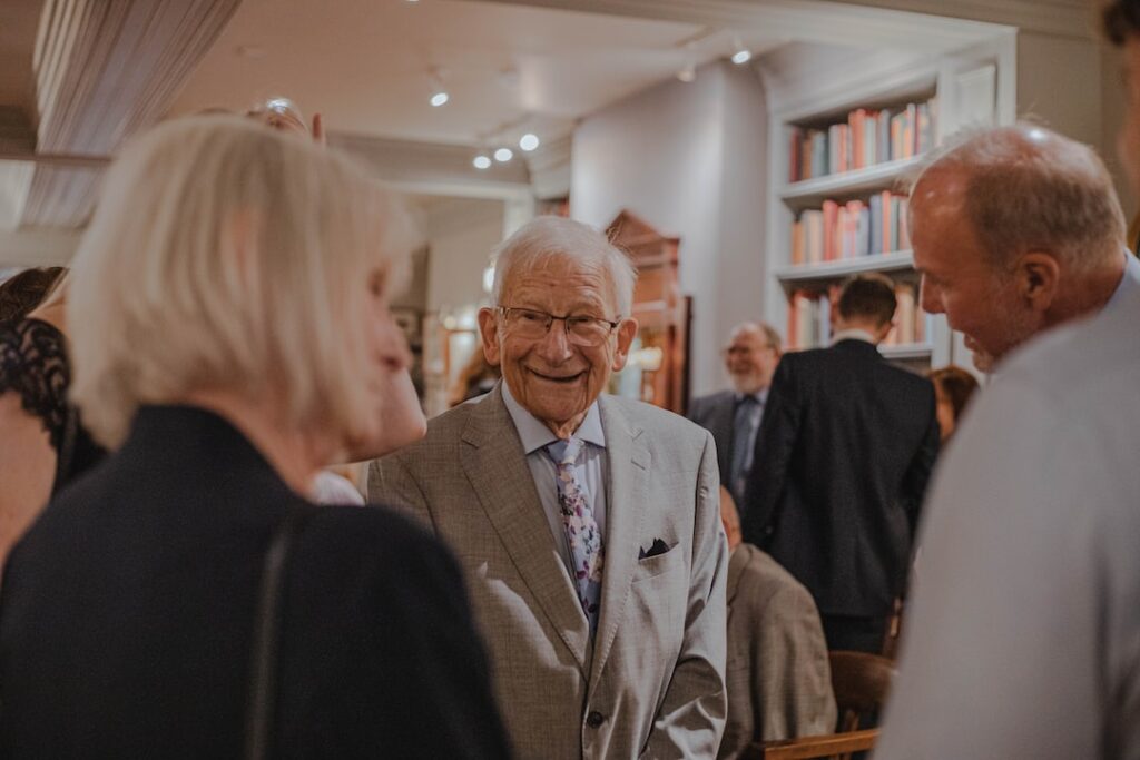 A group of elderly people smiling and conversing at a social event.