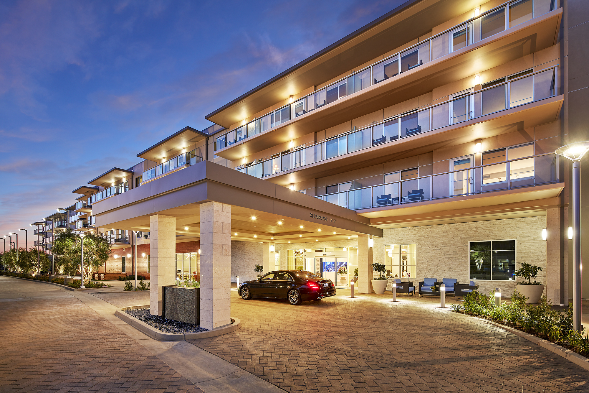 The outside of a Vivante Assisted Living Community, with many windows and balconies, as well as ambient lighting.