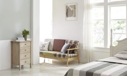 A pristine bedroom with white marble floors, a bed, a small sofa, a dresser, and many windows.