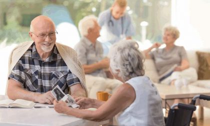 Seniors sitting together at a table, looking at photographs and smiling.