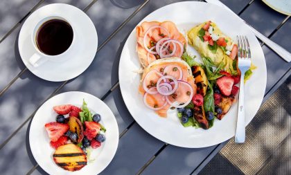 A beautifully plated breakfast, featuring eggs, smoked salmon, fruit, and a coffee.